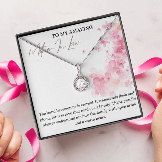 A person unwrapping a necklace gift, with a big cubic zirconia crystal pendant and a white gold finish, with a message card to my amazing mother-in-law.