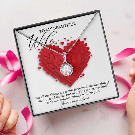 A person unwrapping a necklace gift, with a big cubic zirconia crystal pendant and a white gold finish, with a message card to my beautiful wife.