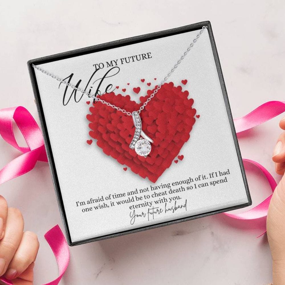 A person unwrapping a necklace gift with ribbon shaped pendant with cubic zirconia crystals and white gold finish, with a message card to my future wife.