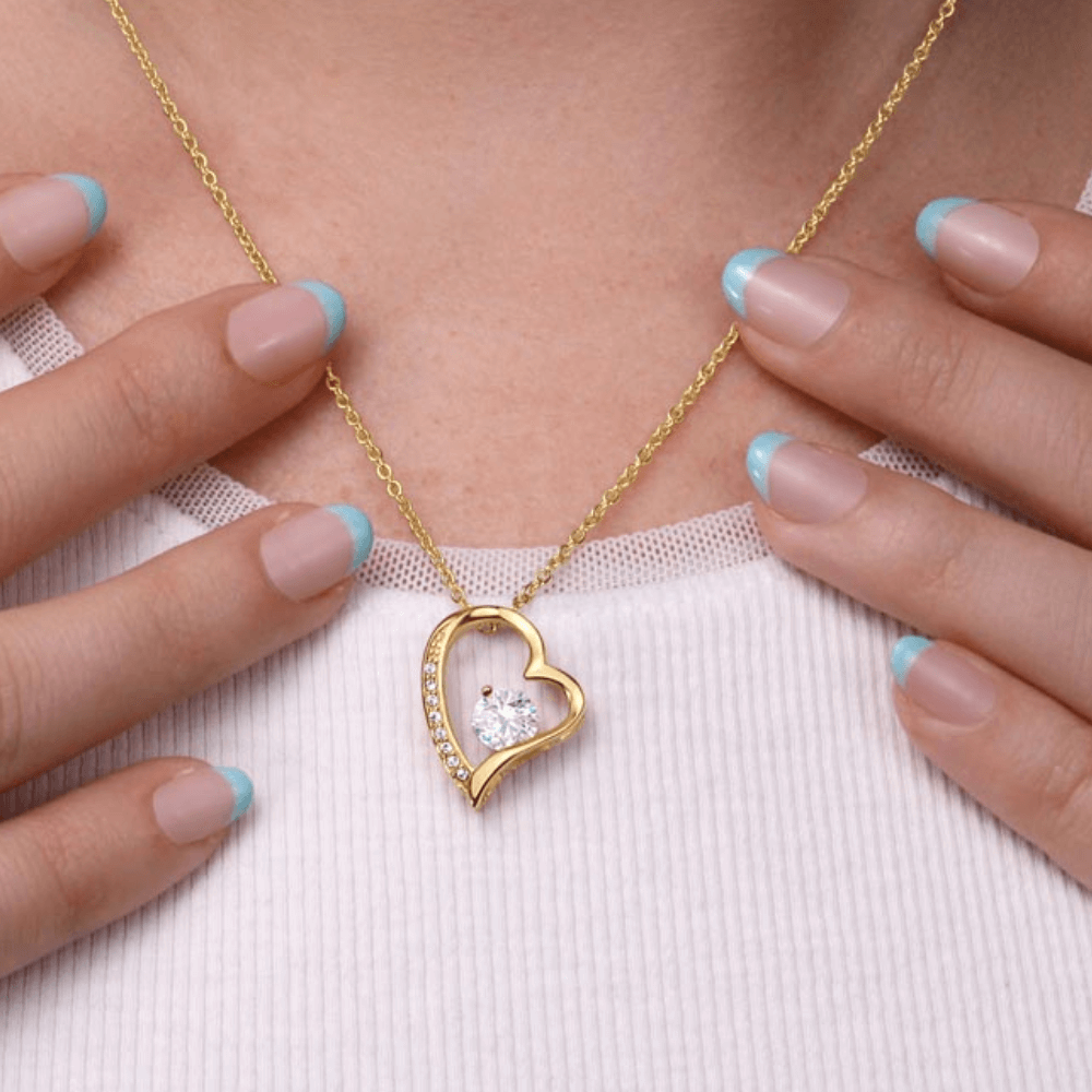 A woman wearing a yellow gold finish necklace gift, featuring a stunning 6.5mm CZ crystal surrounded by a polished heart pendant embellished with smaller crystals.