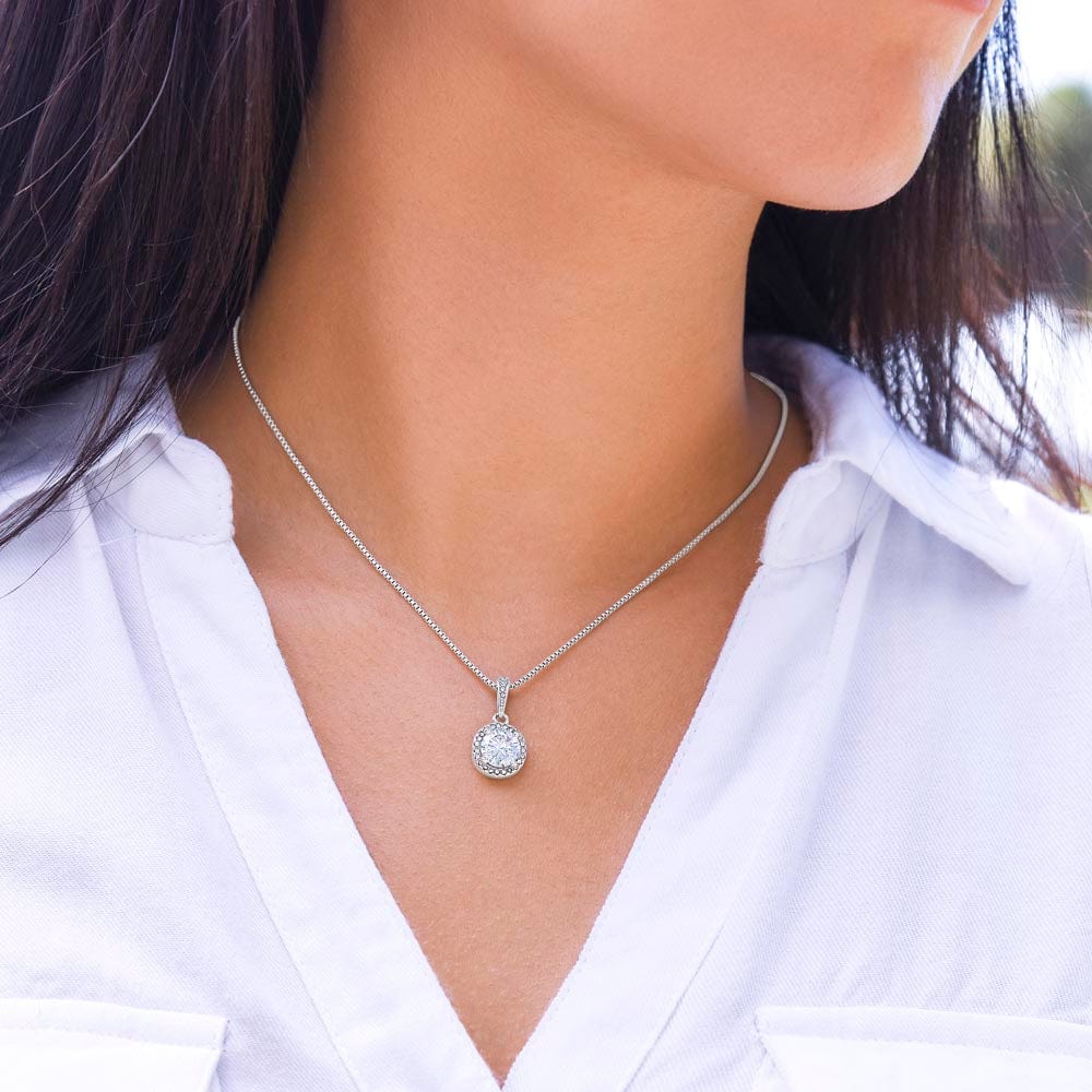 A woman wearing a white gold finish necklace on her neck, with a big cubic zirconia crystal pendant.