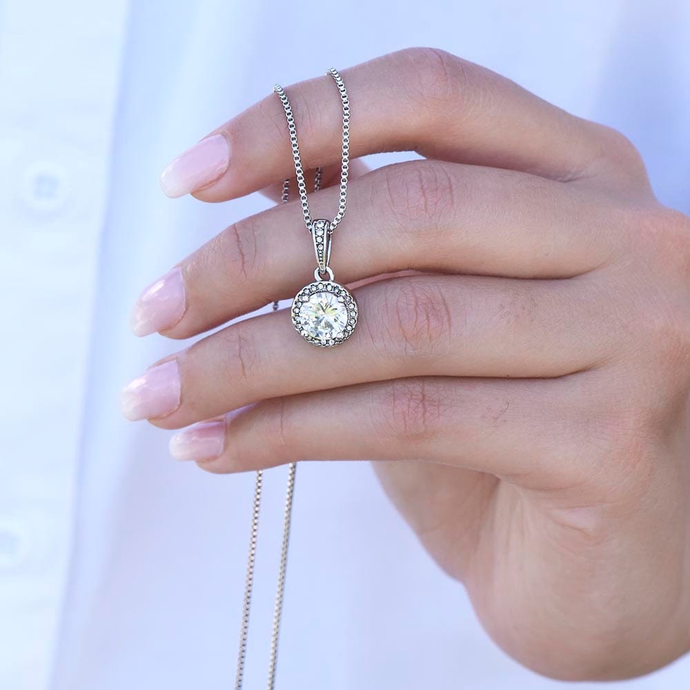 A woman holding a white gold finish necklace, with a big cubic zirconia crystal pendant.