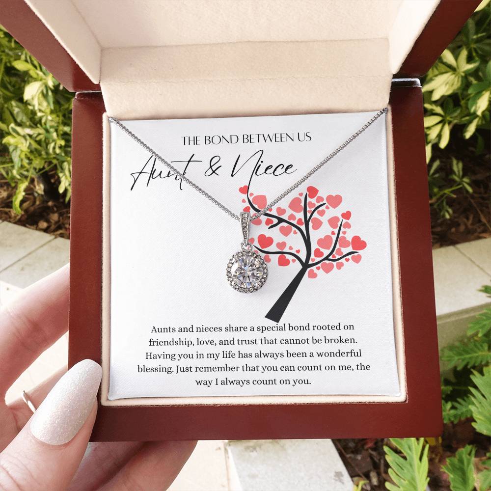 A woman holding a mahogany Jewelry box with a big cubic zirconia crystal pendant and a white gold finish, with a message card for aunts and nieces.