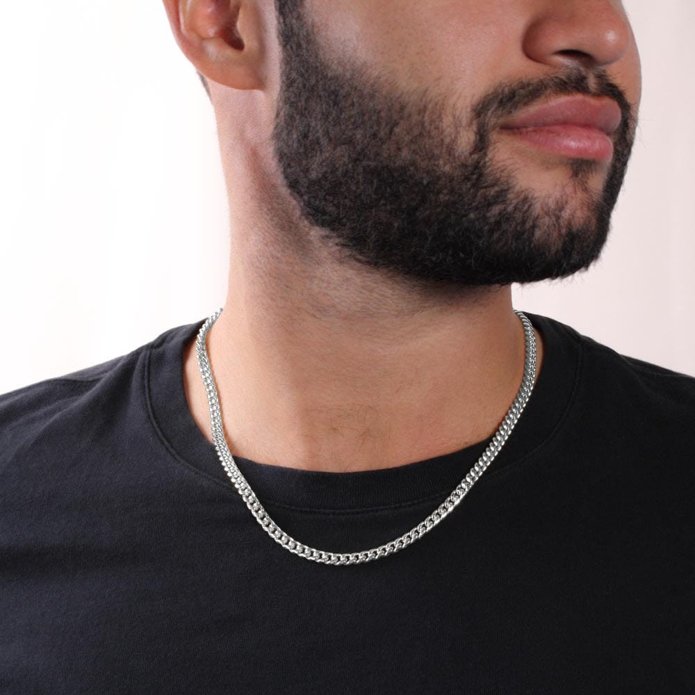 A man wearing a Cuban chain necklace with a white gold finish.