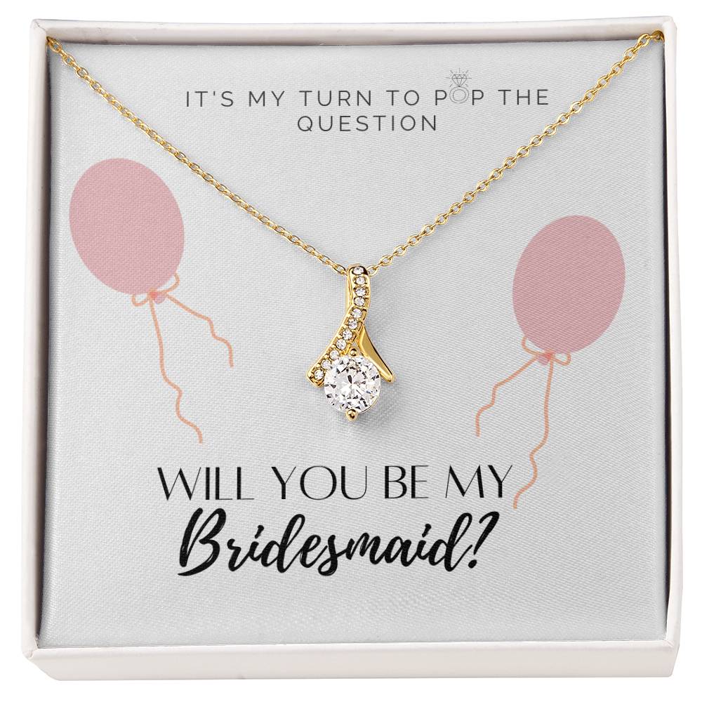 A necklace gift with ribbon shaped pendant with cubic zirconia crystals and a gold finish, with a message card to bridesmaids in a Jewelry box.