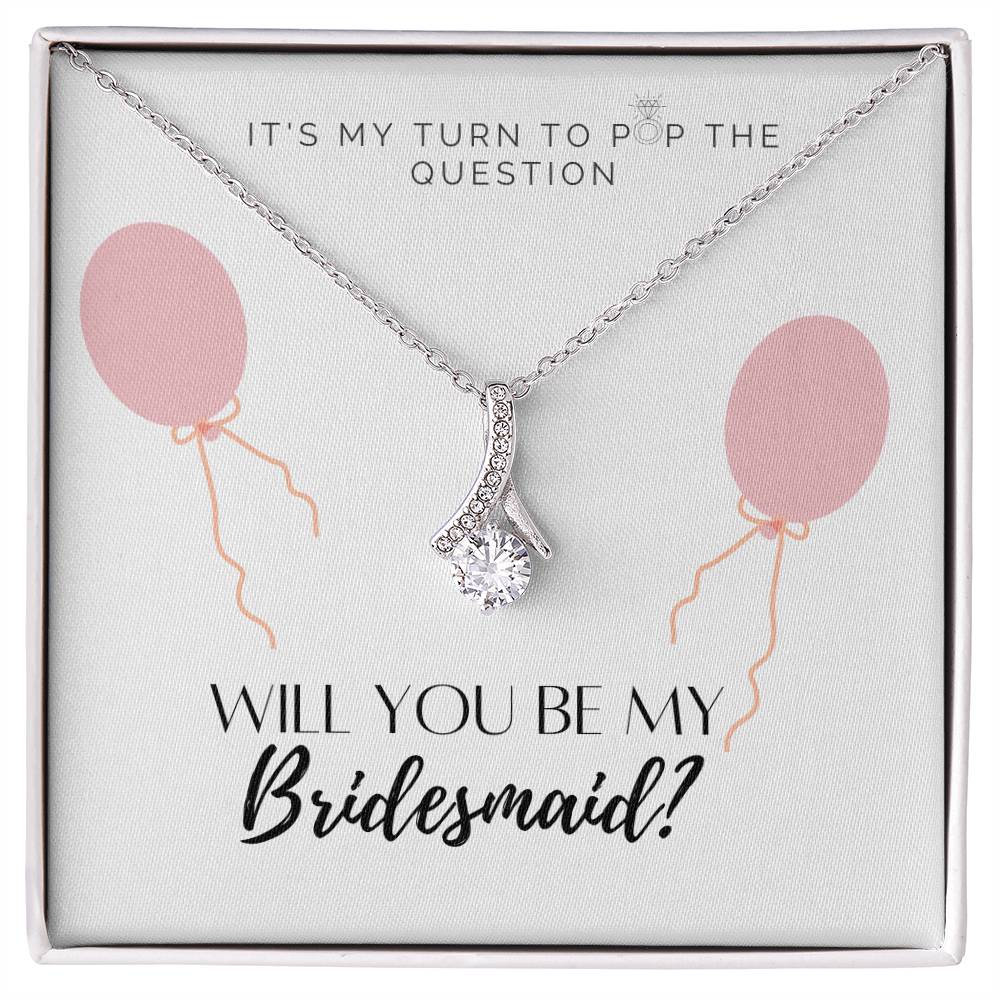 A necklace gift with ribbon shaped pendant with cubic zirconia crystals and a white gold finish, with a message card to bridesmaids in a Jewelry box.