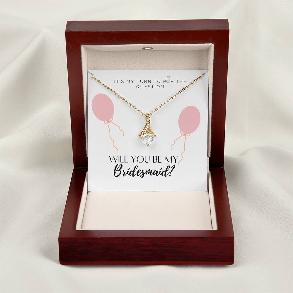 A necklace gift with ribbon shaped pendant with cubic zirconia crystals and a gold finish, with a message card to bridesmaids in a mahogany Jewelry box.