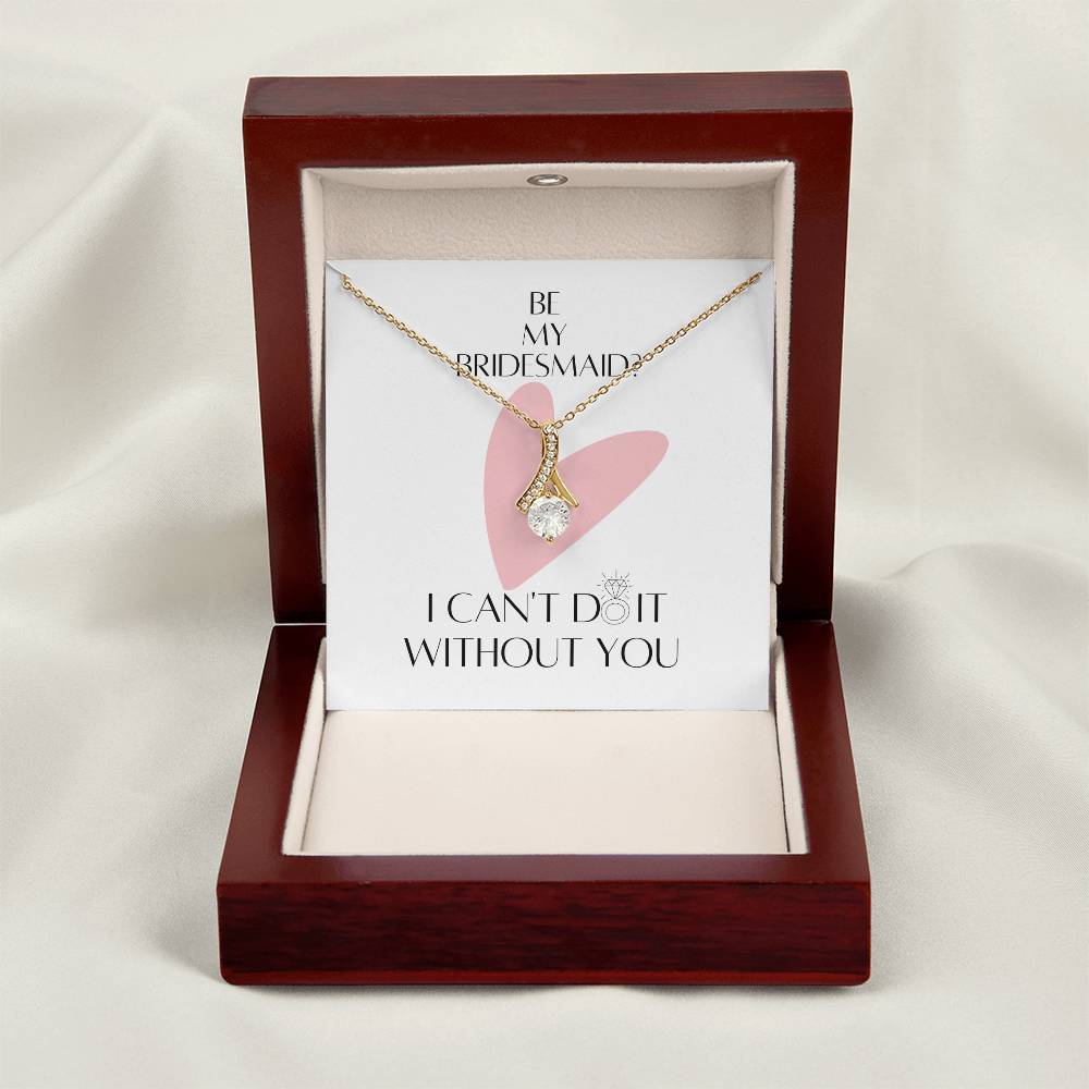 A necklace gift with ribbon shaped pendant made from cubic zirconia crystals and a gold finish with a message card for bridesmaids in a mahogany Jewelry box.
