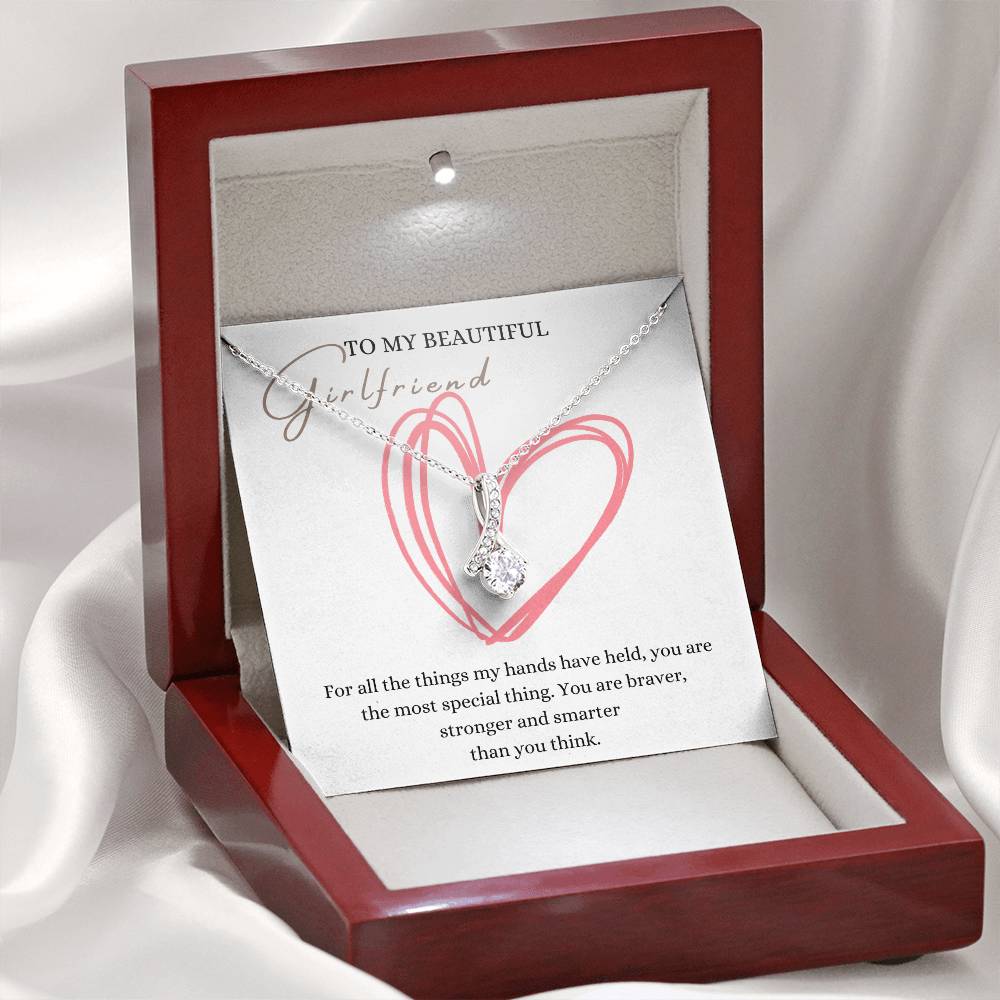 A necklace gift with ribbon shaped pendant with cubic zirconia crystals and white gold finish, with a message card to my beautiful girlfriend in a mahogany Jewelry box.