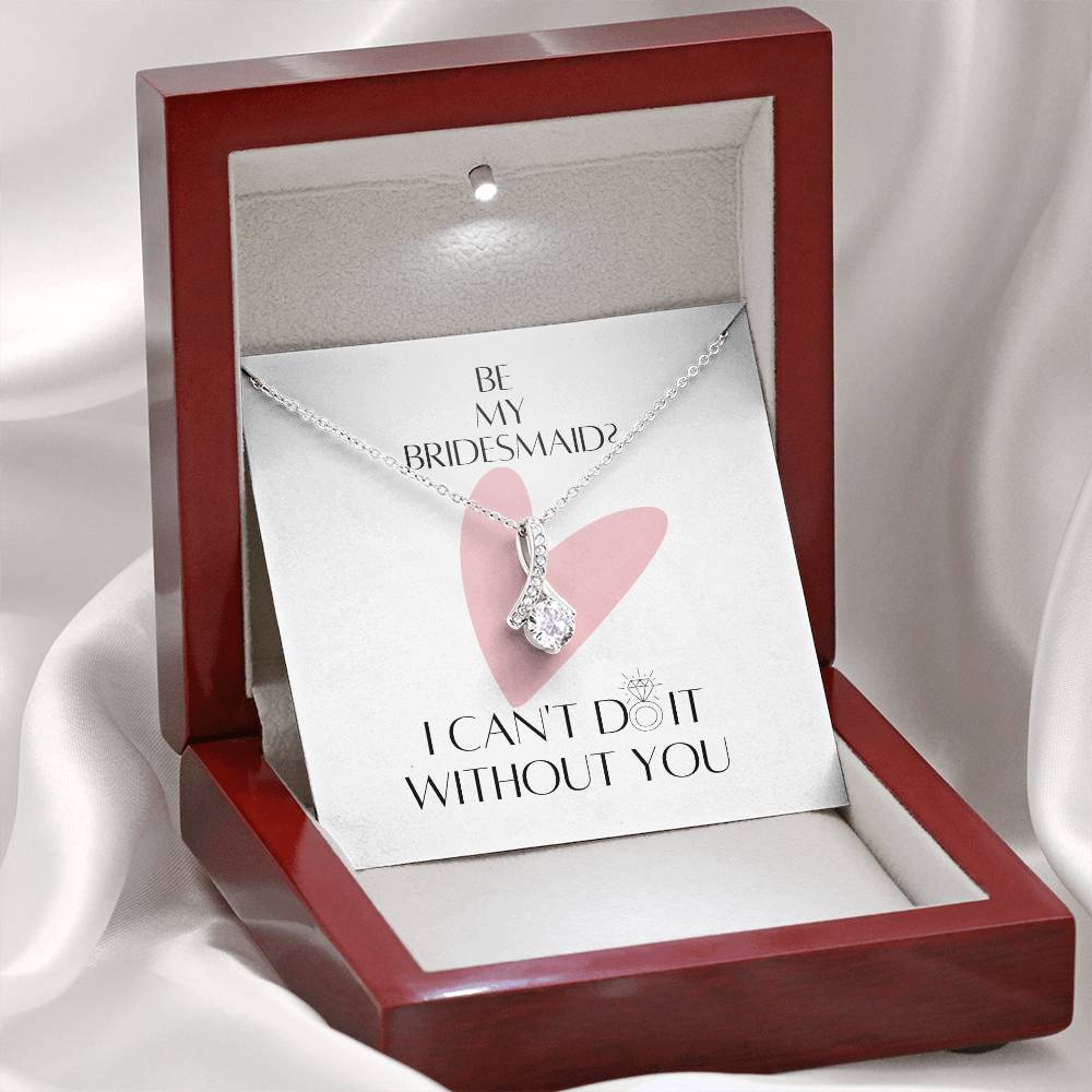 A necklace gift with ribbon shaped pendant made from cubic zirconia crystals and a white gold finish with a message card for bridesmaids in a mahogany Jewelry box.