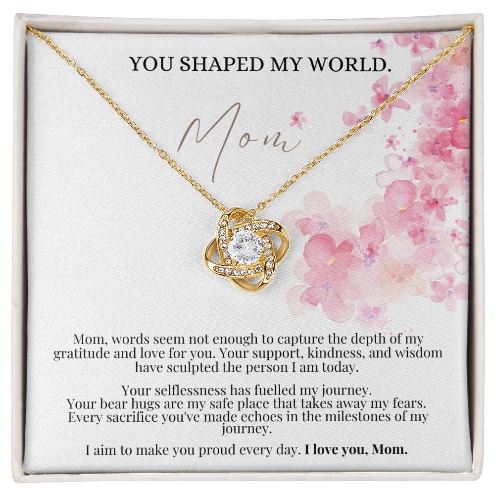 A yellow gold finish necklace gift, with a knot pendant embellished with premium cubic zirconia crystals, and a message card to mom, in a Jewelry box.
