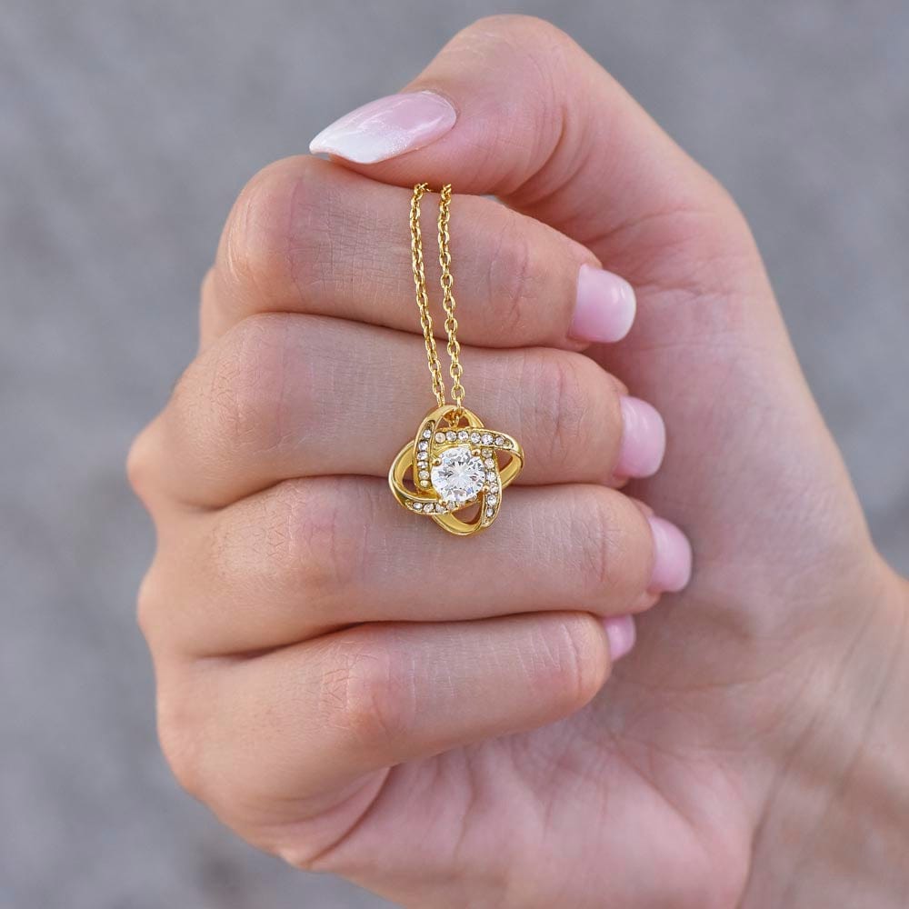 A yellow gold finish necklace gift, with a knot pendant embellished with premium cubic zirconia crystals, and a message ca