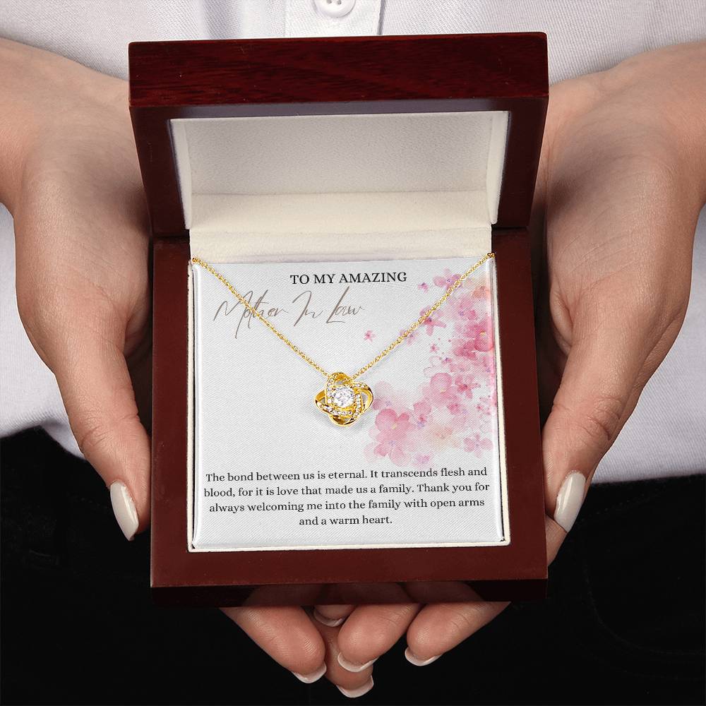 A yellow gold finish necklace gift, with a knot pendant embellished with premium cubic zirconia crystals, and a message card to my amazing mother-in-law, in a mahogany Jewelry box. 