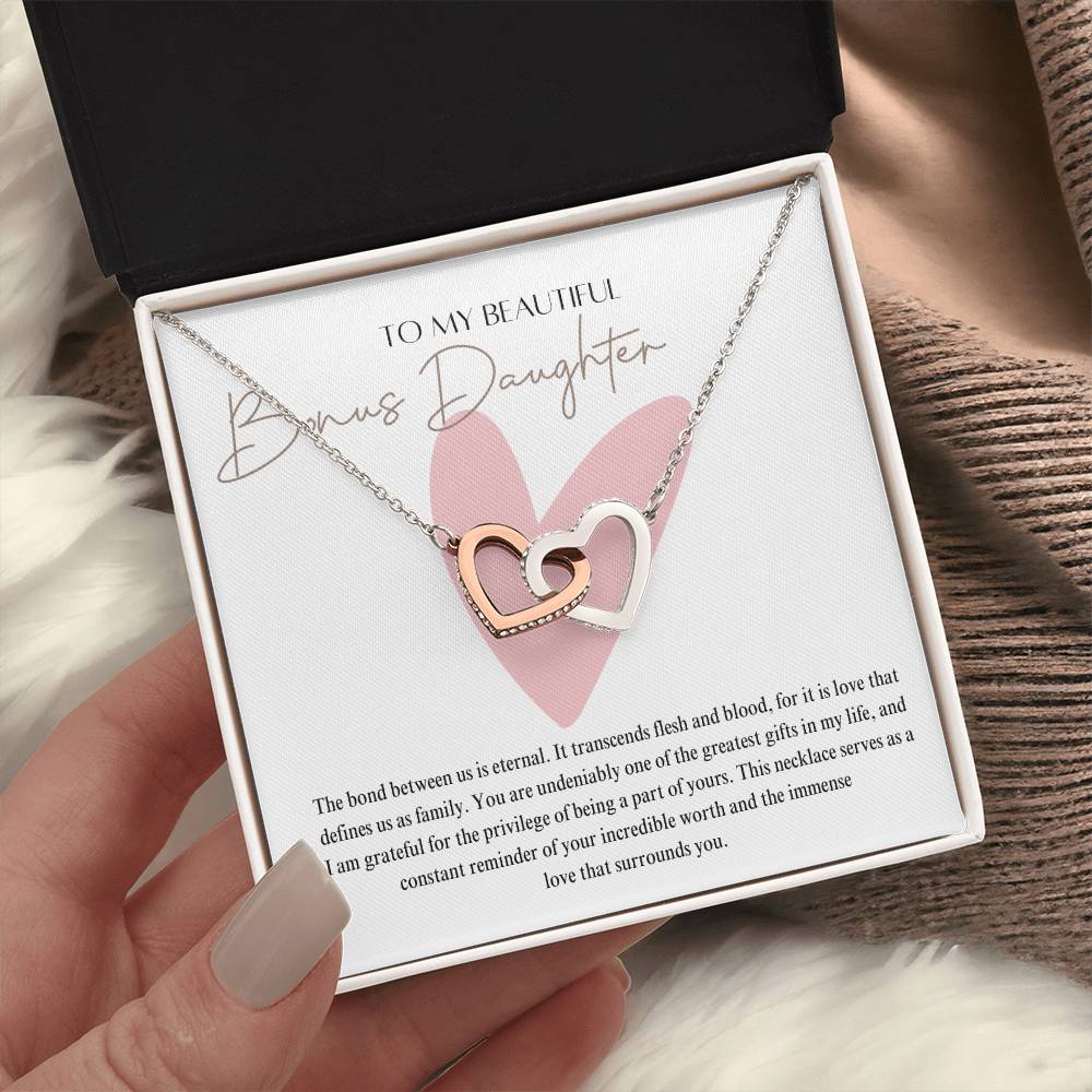A woman holding a jewelry box, with a necklace with two connected hearts embellished in cubic zirconia crystals and white gold finish, with a message card to my beautiful bonus daughter.