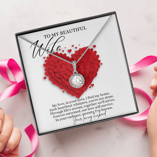 A person unwrapping a necklace gift, with a big cubic zirconia crystal pendant and a white gold finish, with a message card to my beautiful wife. 
